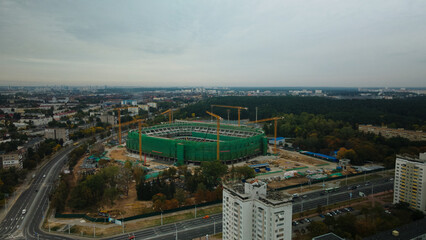 Building a stadium in a big city. Construction site among urban areas. Aerial photography.