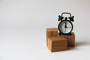 cardboard boxes and black alarm clock on white background, fast shipping. transportation speed. storage time in the warehouse. delayed delivery. quick carriage.