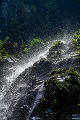 A waterfall in the middle of a forest with a stone wall around it