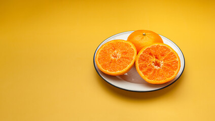 Top view of fresh oranges in a white dish over a yellow background