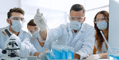 medical doctors are working with test tubes and microscope at th