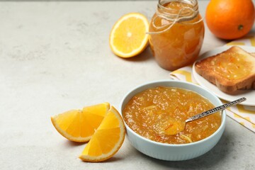 Delicious orange marmalade in bowl on light grey table. Space for text