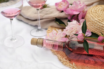 Bottle of rose wine and peonies on white fabric