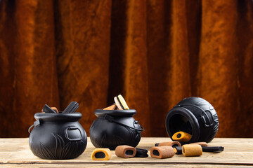 Three small toy witches' cauldrons with different candies stand on a wooden table, with a vintage...