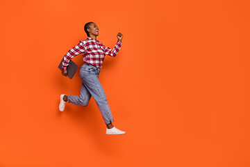 Full body profile photo of energetic pretty girl hurry jumping look empty space isolated on orange color background