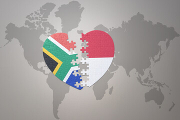 puzzle heart with the national flag of south africa and indonesia on a world map background. 3D illustration