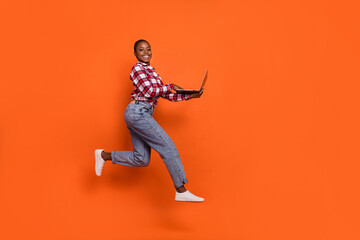 Full size photo of active sporty lady jump rush use wireless netbook isolated on orange color background
