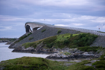 Wonderful landscapes in Norway. Vestland. Beautiful scenery of famous bridges on the Atlantic Road scenic route. Calm sea at the sunset in a cloudy day. Sunrays through clouds. Selective focus