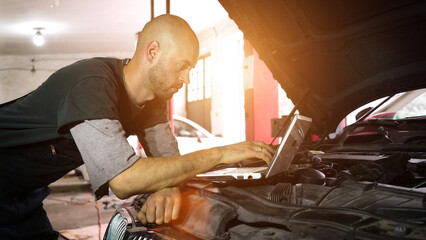Fototapeta premium auto repairman diagnoses a car using a computer. car workshop. close-up