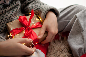 the child is holding a gift in craft paper and with a red ribbon on a golden garland background
