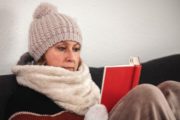 woman with warm winter clothes is reading a book