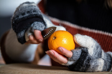 a woman with gloves peels an orange