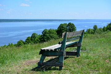 wooden bench on the edge of the mountain with view to the river