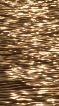 Reflected sun in the waves of the sea at sunset. Vertical 4K