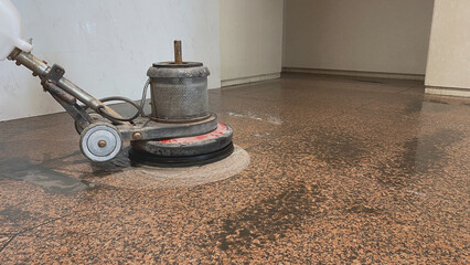 Cleaning a red granite interior floor with a professional scrubber
