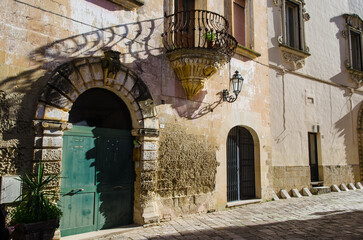 Fototapeta na wymiar Il portone verde di un palazzo storico di Corigliano d'Otranto illuminato dal sole del mattino che crea l'ombra della ringhiera del balcone