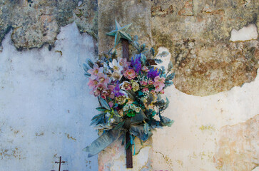Un mazzo di fiori di metallo  sul muro scrostato di una cappella di famiglia nel cimitero di Tricase, borgo del Salento in Puglia - obrazy, fototapety, plakaty