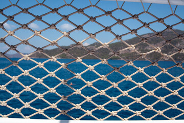 Rope net texture against blue sea background. A material net that is a decoration on a yacht, performing protective functions. Close up.