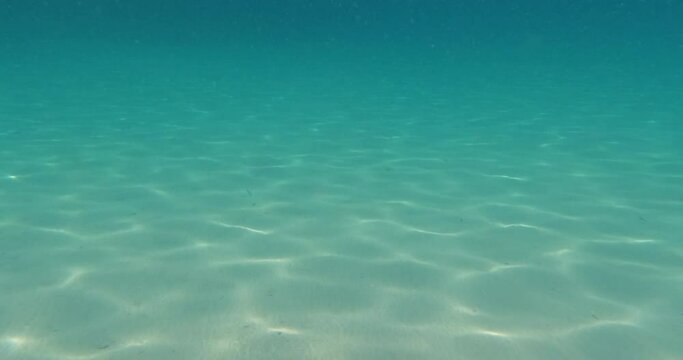 Underwater footage scene of moving through turquoise color sea water. Ripple sunlight rays on sea bottom. Beautiful under water surface seascape at Aegean sea. 4K video slow motion.	