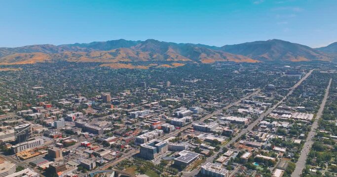 Helicopter flying over the green city on sunny daytime. Mountains of Utah with wonderful Salt Lake City at the foot. Top view.