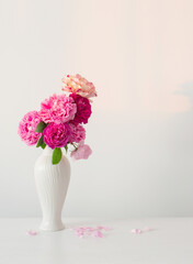 pink roses in white vase on table  on background white wall