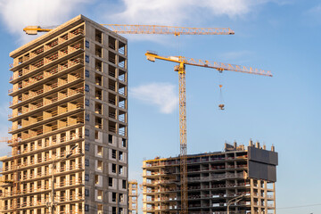 Fototapeta na wymiar Construction site with 2 cranes on bright sunny day.