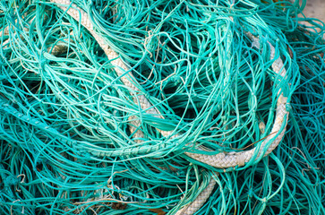 Dettaglio di una rete da pesca verde con corde bianche stesa ad asciugare al sole 