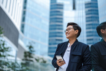 Smiling young businessman using mobile phone in the city

