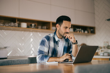 Focused man working from home, over the laptop, looking serious.