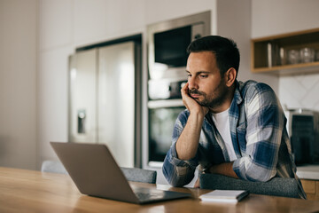 Obraz premium A man getting tired of work, using a laptop, working online, at home.