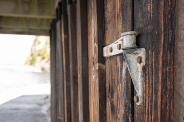 Retro iron door hinge that has corrosion over time and rusted bolts outdoors. Detail of an old wooden gate.