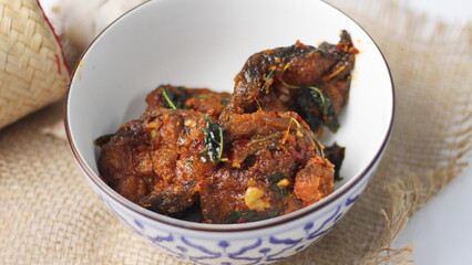 Spicy Stir Fried Catfish served in a Thai style patterned bowl on a white table.