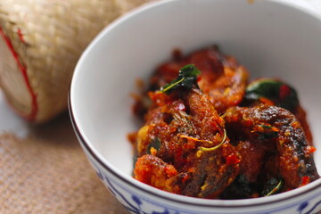 Spicy Stir Fried Catfish served in a Thai style patterned bowl on a white table.