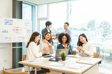 Young and successful mixed race, asian business people working on project together, sitting at table in boardroom.