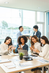 Young and successful mixed race, asian business people working on project together, sitting at table in boardroom.