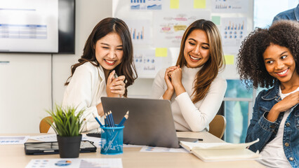 Young and successful mixed race, asian business people working on project together, sitting at table in boardroom.