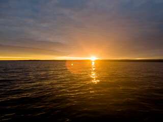 Obraz premium Water surface. View of a Sunset sky background. Dramatic gold sunset sky with evening sky clouds over the lake. Clear water texture. Landscape. Water reflection