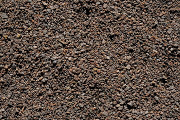 A texture of many little grey white stones with sand laying on ground