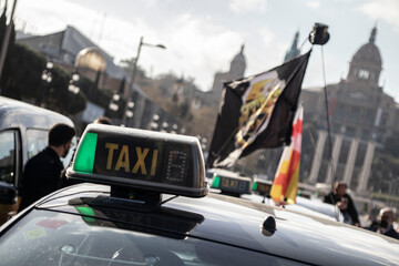 Detalle de la señal luminosa de un taxi con bandera de fondo