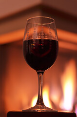 Glass with red wine and the fireplace as background
