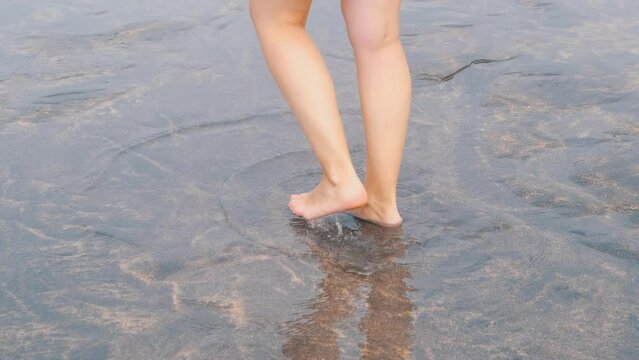 Legs of a young girl walking on the seashore in winter
