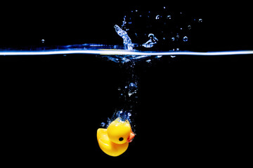 Yellow rubber duck dropped in water with splashes