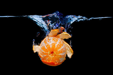 Peeled tangerine dropped in water with splashes