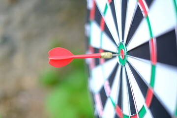 Red dart arrow hitting in the target center of dartboard Target hit in the center blur background.