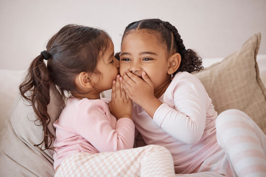 Girl, friends or children whisper secret to best friend on home sofa while relax together on play date. Communication, conversation and sisters or youth kids gossip at fun slumber party or sleepover