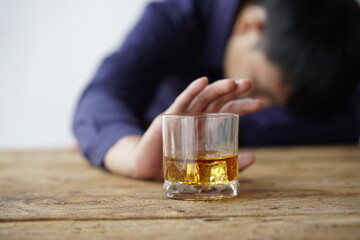 Businessman handshake after make deal, alcoholism, alcohol addiction and people concept - male alcoholic with glass of whiskey lying or sleeping on table 