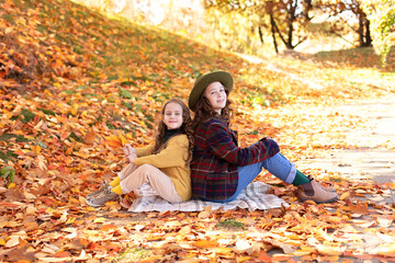 Young beautiful happy two small girls in autumn clothes. Happy little sisters hugging on an autumn background for halloween. A smiling girlfriends walking in fall park. concept happy family, childhood