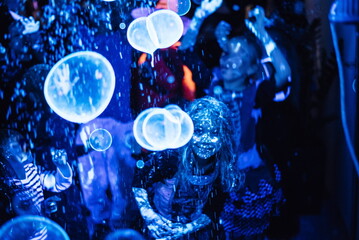 Children's disco. Children have fun at the soap bubble show. Fluorescent paint on the face in ultraviolet. Film noise. Diffuse focus. Halloween party