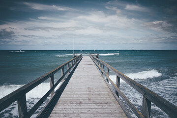 wooden pier at rough baltic sea on dark and windy day, German seaside