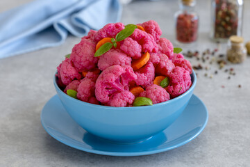Marinated Cauliflower Salad with carrot and beet served in a blue bowl on a light background. Pink pickled vegetables.  